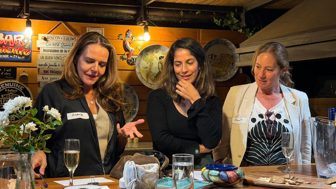 Tres participantes conversando con una copa de espumante